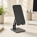 Foldable dark aluminium phone stand on a desk